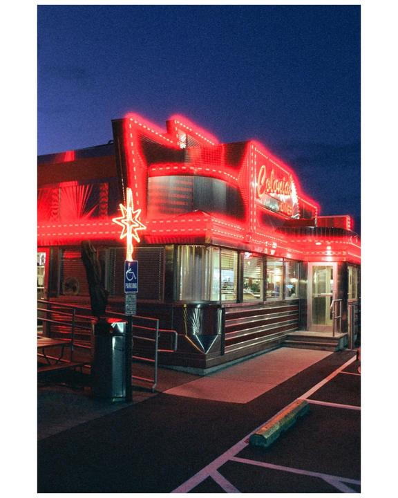 A diner with bright red neon lights illuminates the night.