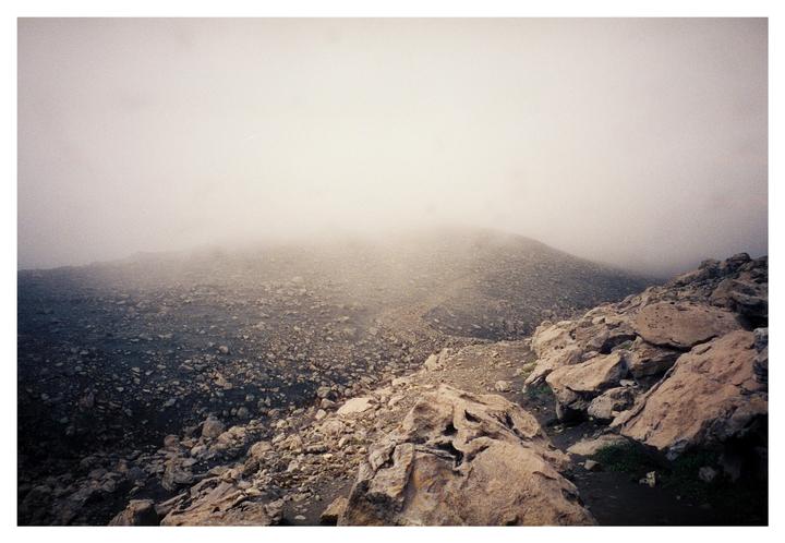 A rocky, barren landscape is covered in a thick fog.
