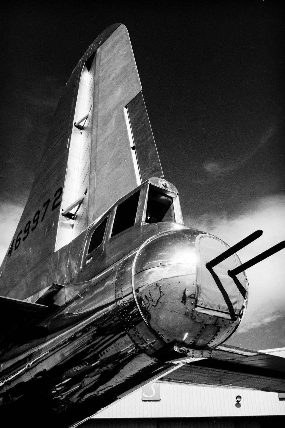 The tail gunner position and tail of a Boeing B29 aircraft are visible against a cloudy sky.
