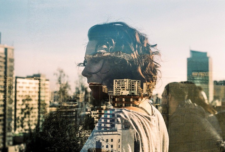 A double exposure shows a woman's profile overlaid with a cityscape under a bright sky.