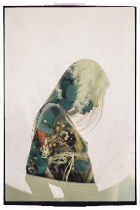 A double exposure shows the silhouette of a woman with long hair overlaid with an image of plants and flowers.