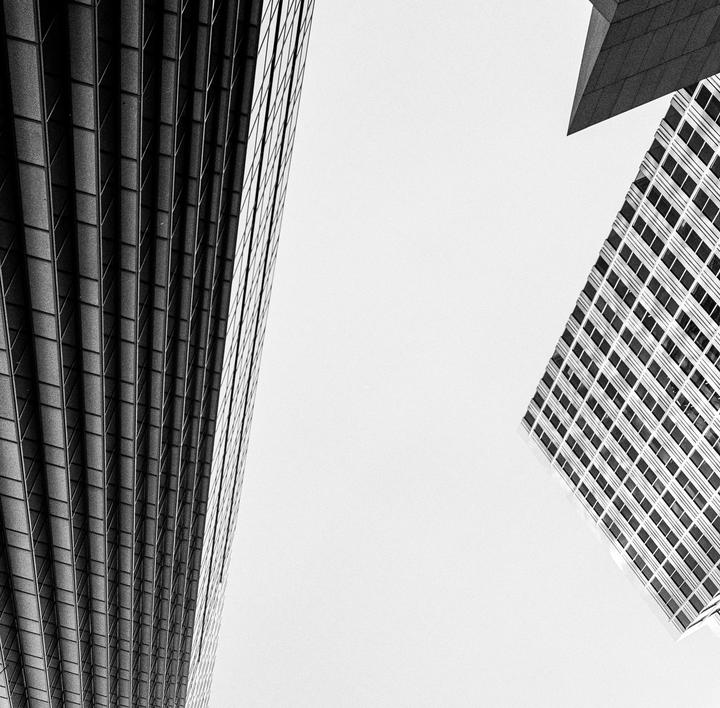 Three modern buildings are visible from a low angle against a bright sky.