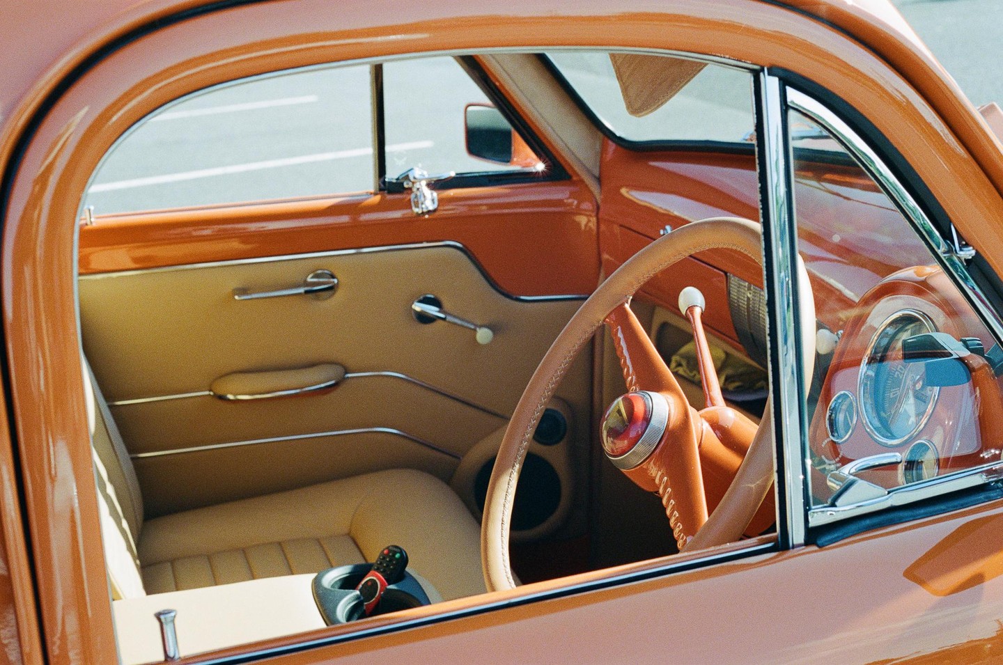The interior of an orange classic car is visible through the open window.