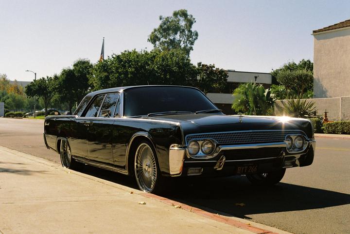 A black vintage car with chrome details is parked on the side of a street.