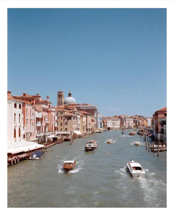 A wide canal with boats is surrounded by buildings under a clear sky.