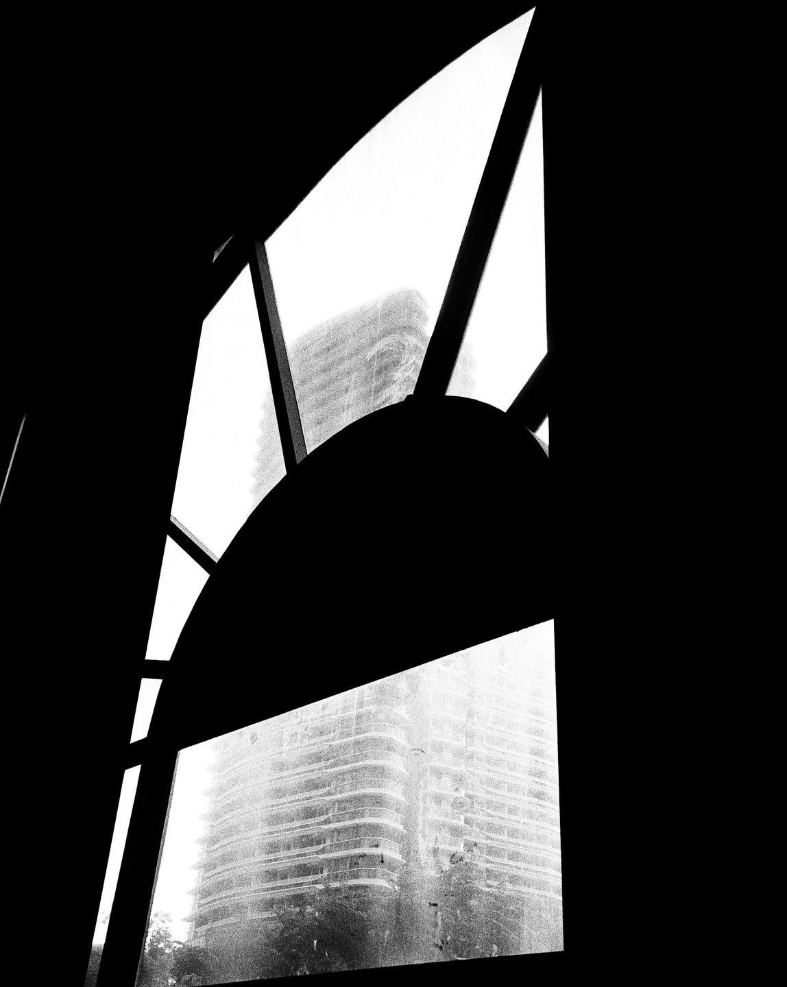 A tall building is visible through a window with an arched top and geometric panes.