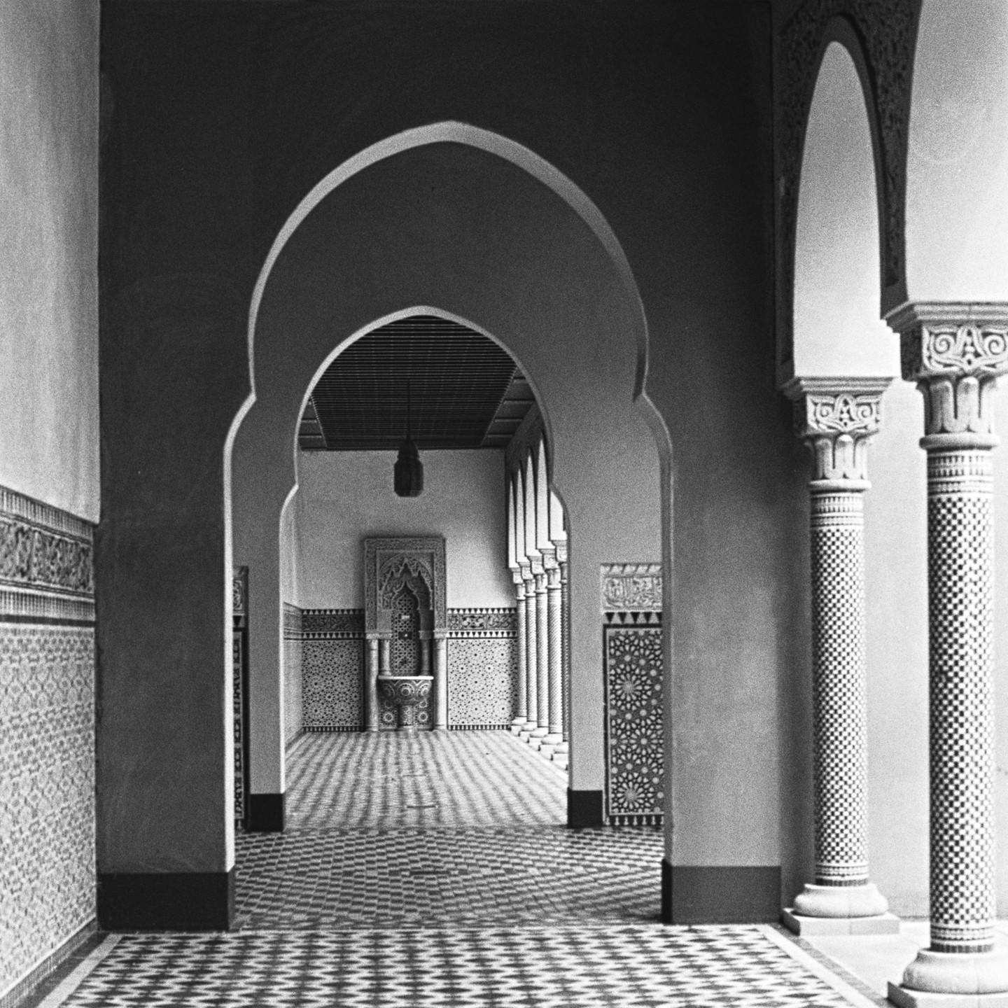 A long hallway with patterned tile walls and floor leads to a fountain at the far end.