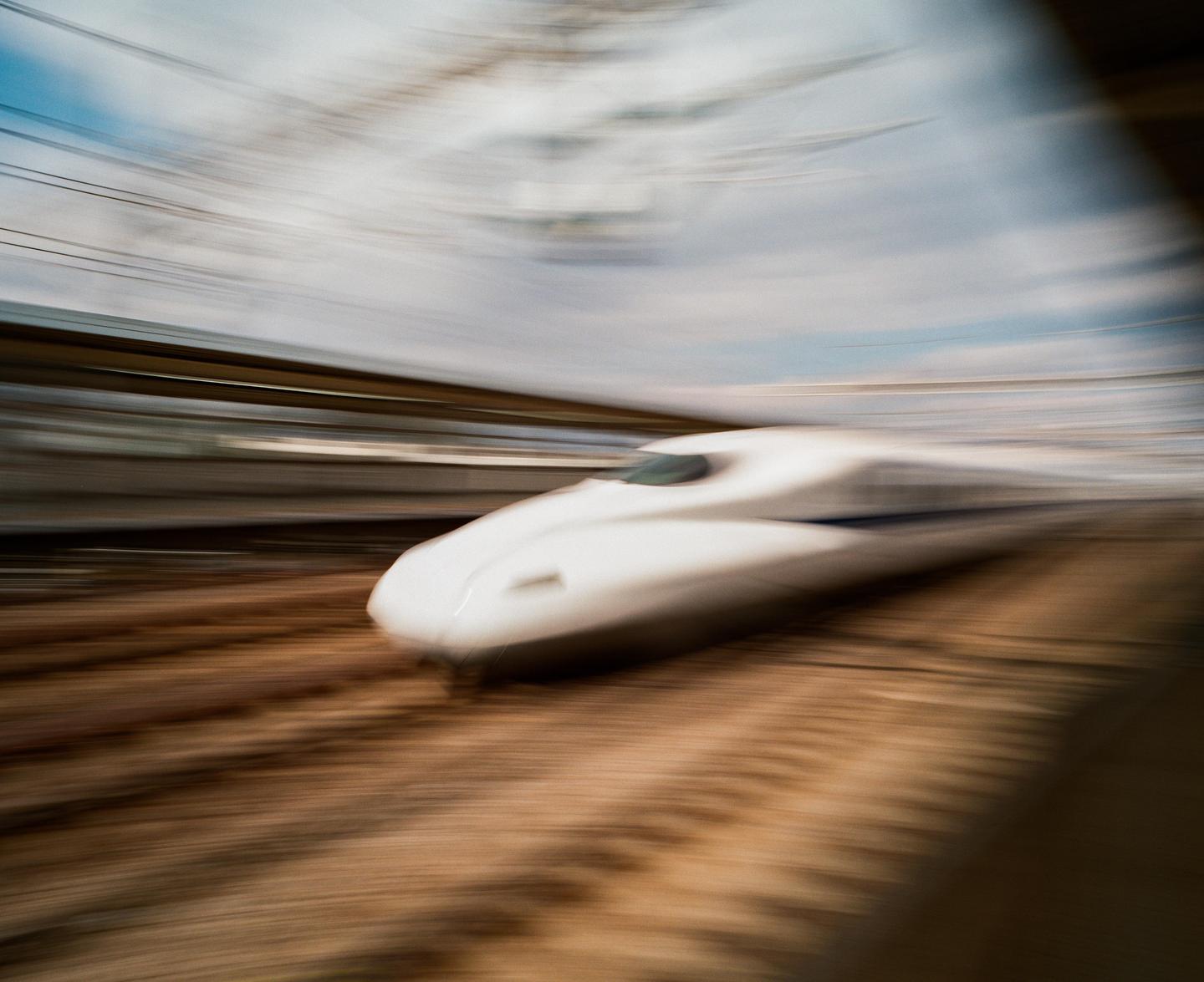 A white bullet train speeds past with motion blur.