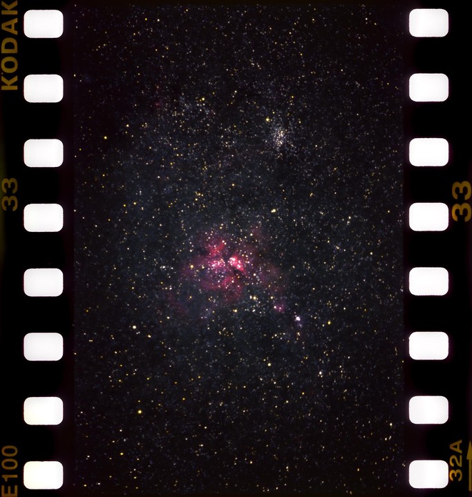 A nebula with pink and red hues is visible among many stars in the night sky.