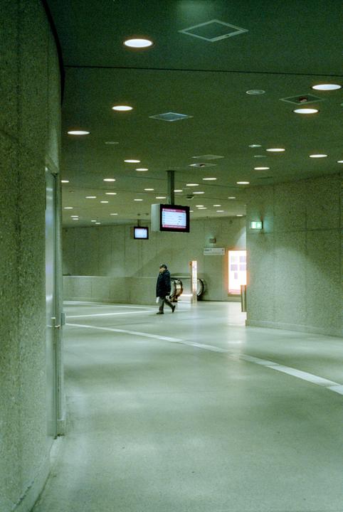 A man walks through a brightly lit metro station.