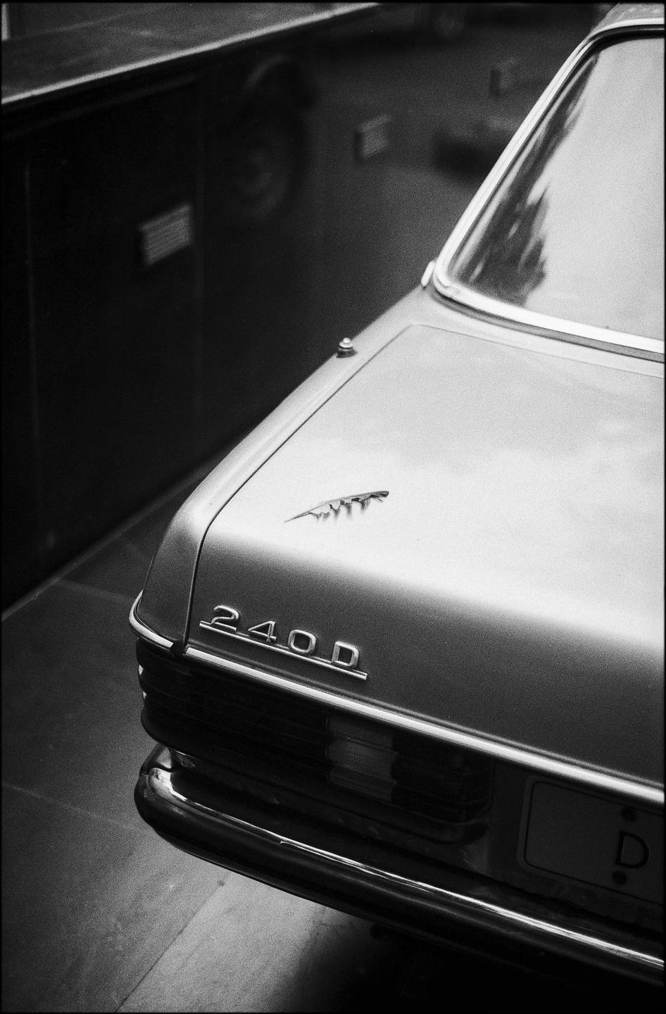 The rear of a car with "240D" and a feather emblem on the trunk is visible.
