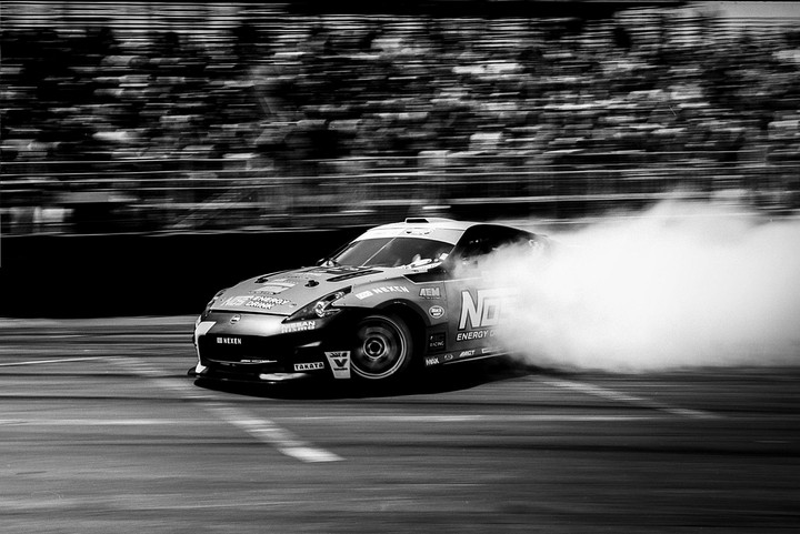 A race car drifts around a track, leaving a trail of smoke behind it.