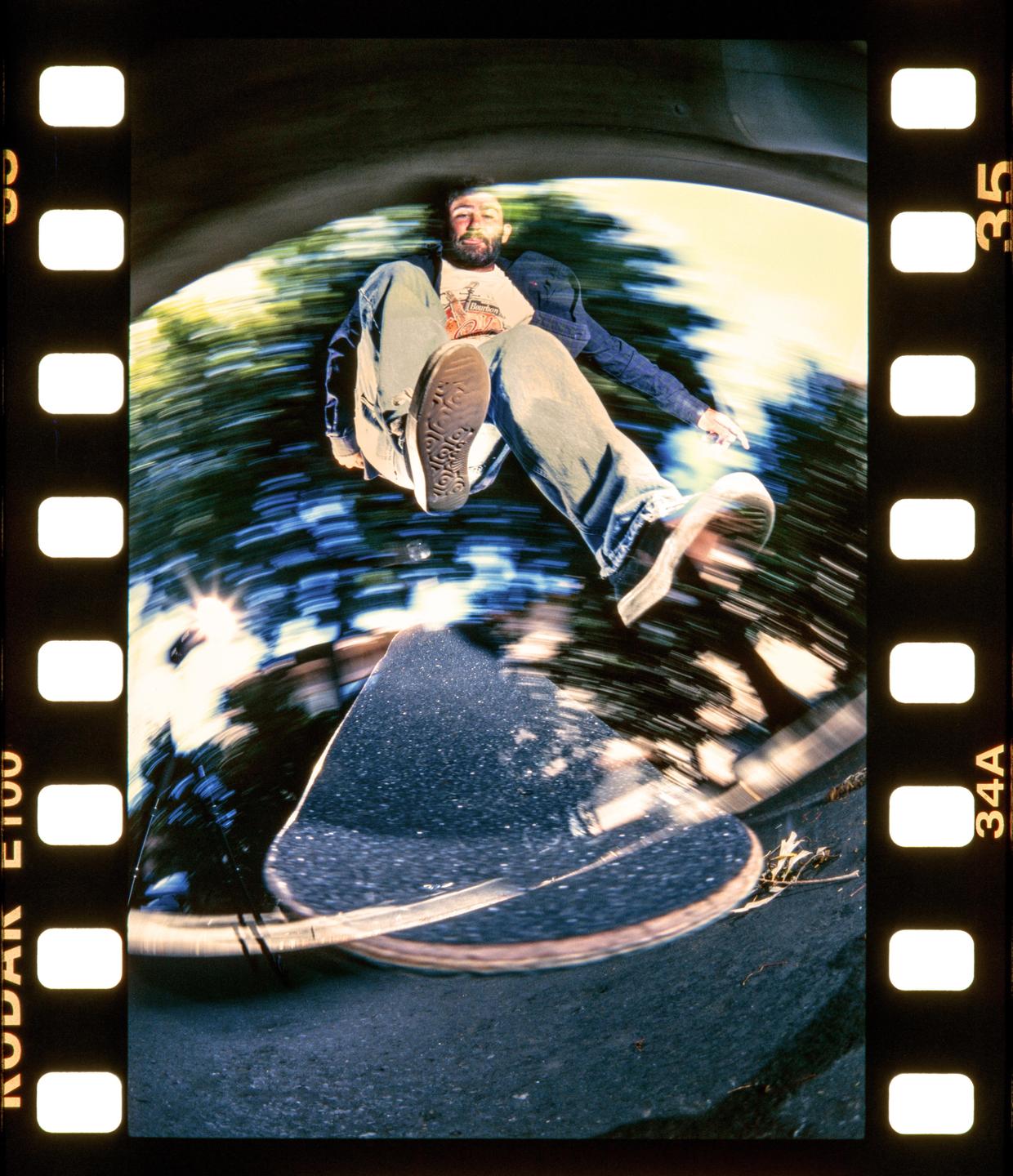 A man on a skateboard is captured from a low angle, with motion blur in the background.