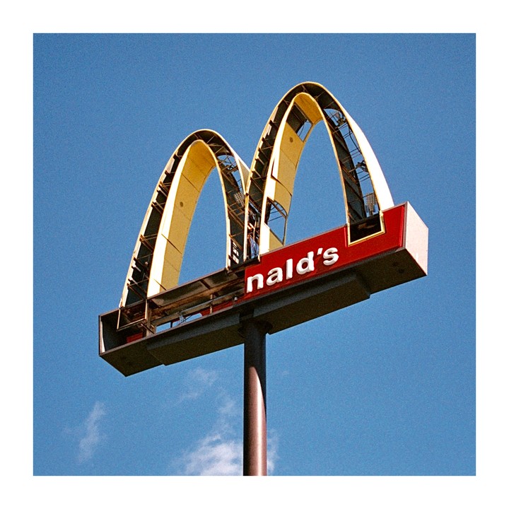 A McDonald's sign with the letters "nald's" visible is set against a clear blue sky.