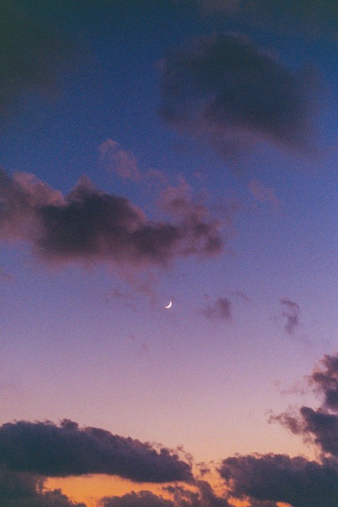 A crescent moon is visible in a purple and orange sky with clouds.