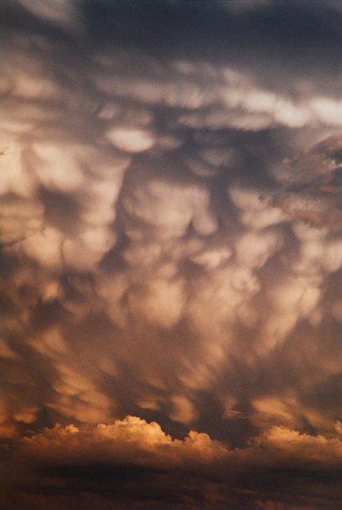 Dark clouds fill the sky, with some illuminated by a warm light from below.
