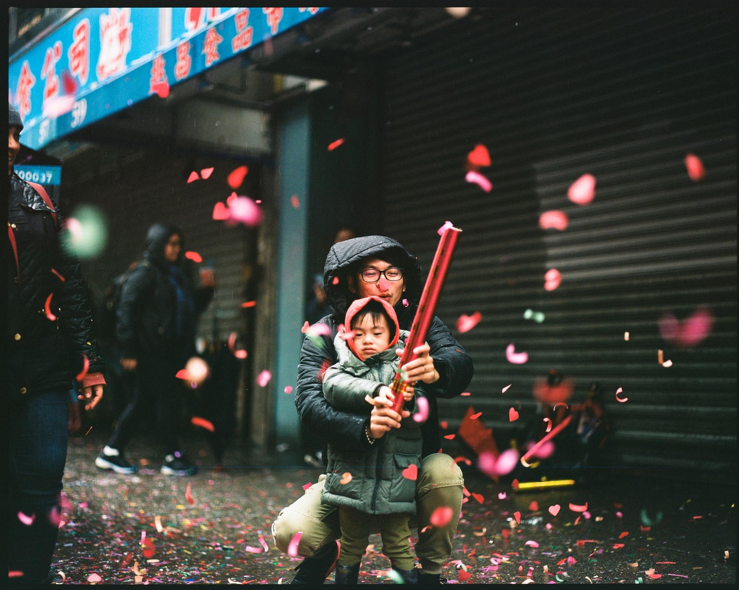 A man and a child are on a street with confetti falling around them.