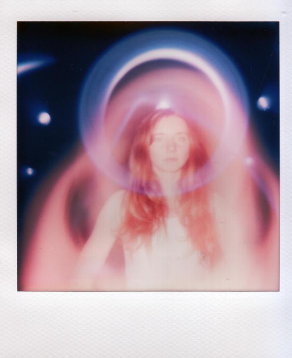 A woman with long hair is surrounded by a pink and blue aura.