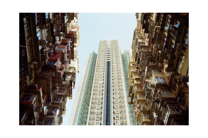 Three tall buildings are visible from a low angle, with two older, more cluttered buildings framing a newer, taller building in the center.