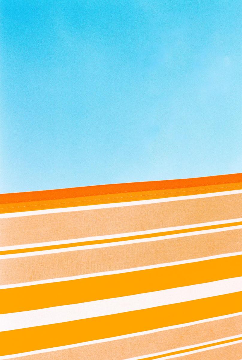 A blue sky is visible above a striped awning.