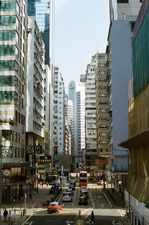 A busy street in Causeway Bay, Hong Kong, is lined with tall buildings and features cars and a double-decker bus.