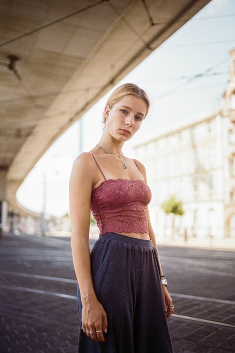 A woman stands on a street with an overpass above her.