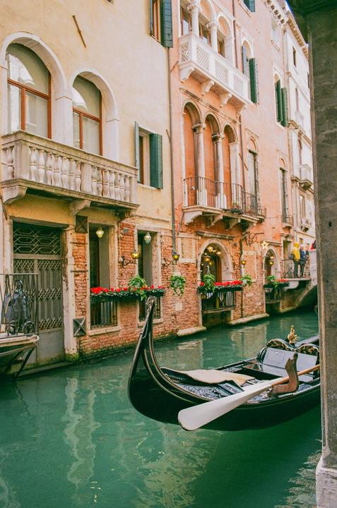 A gondola floats on a canal surrounded by buildings with balconies and window boxes.