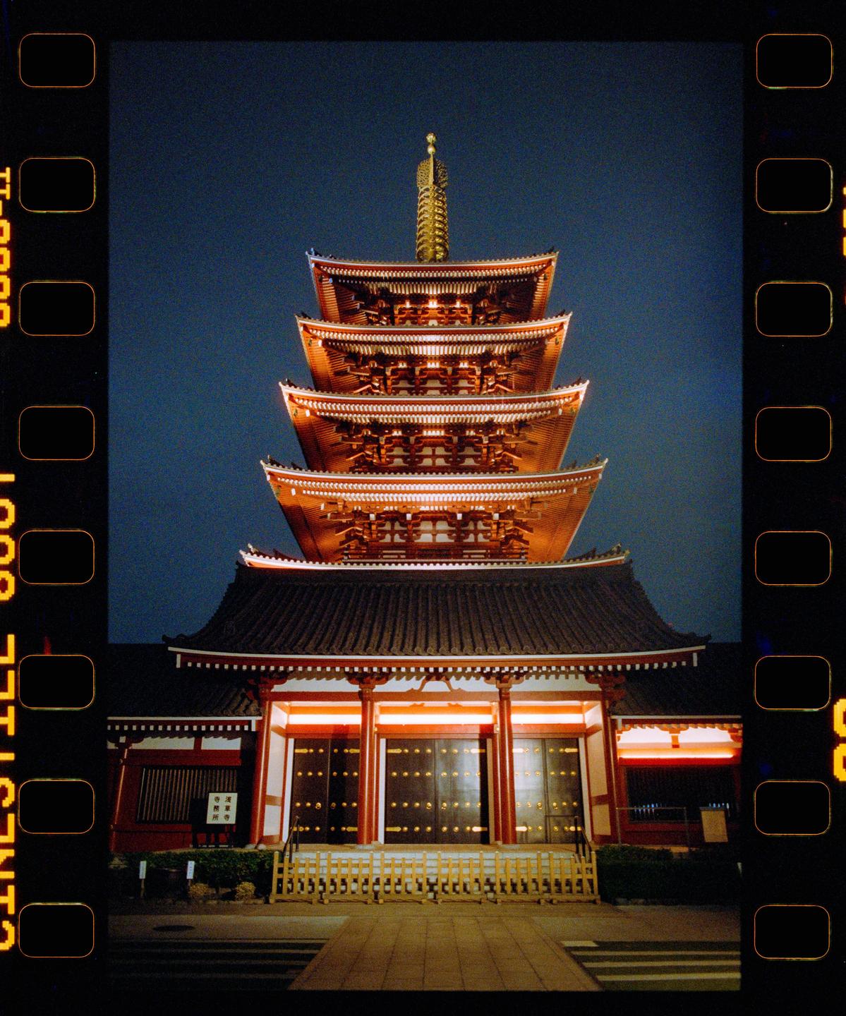A multi-tiered pagoda with illuminated eaves stands against a dark blue night sky.