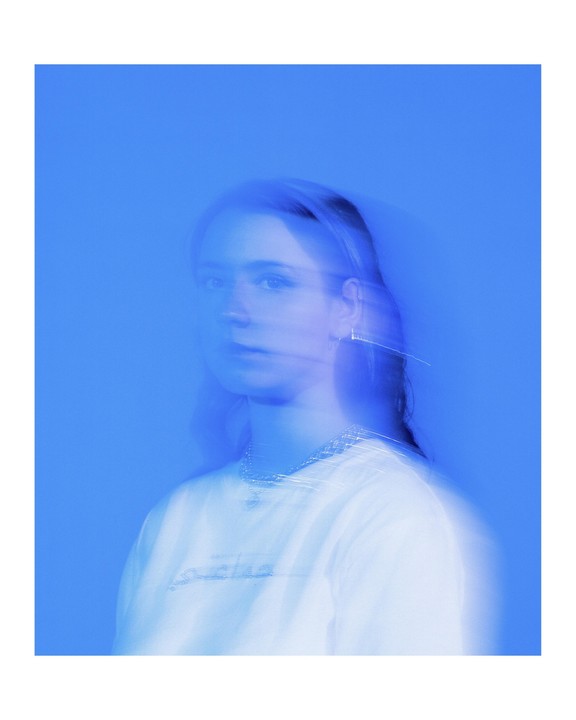 A woman with long hair and a necklace is visible in a blue-toned portrait with motion blur.
