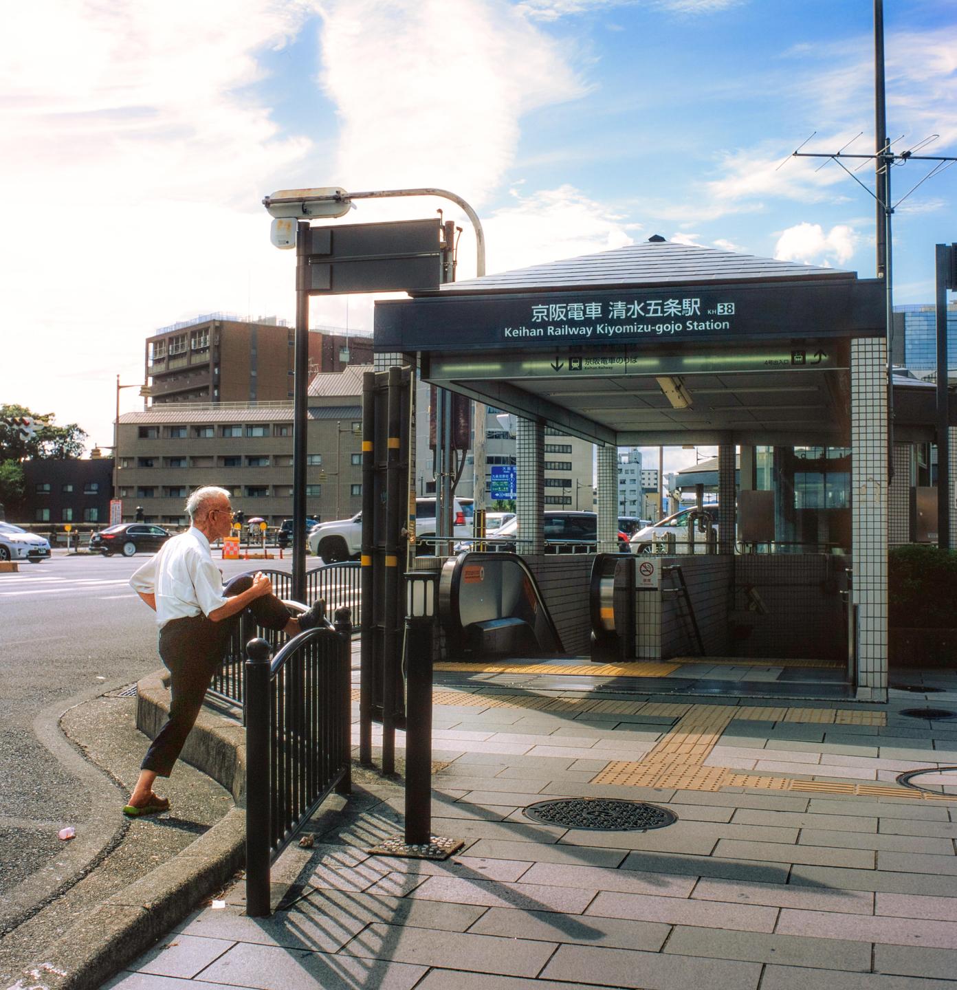A man stretches his leg on a railing next to the Keihan Railway Kiyomizu-gojo Station.