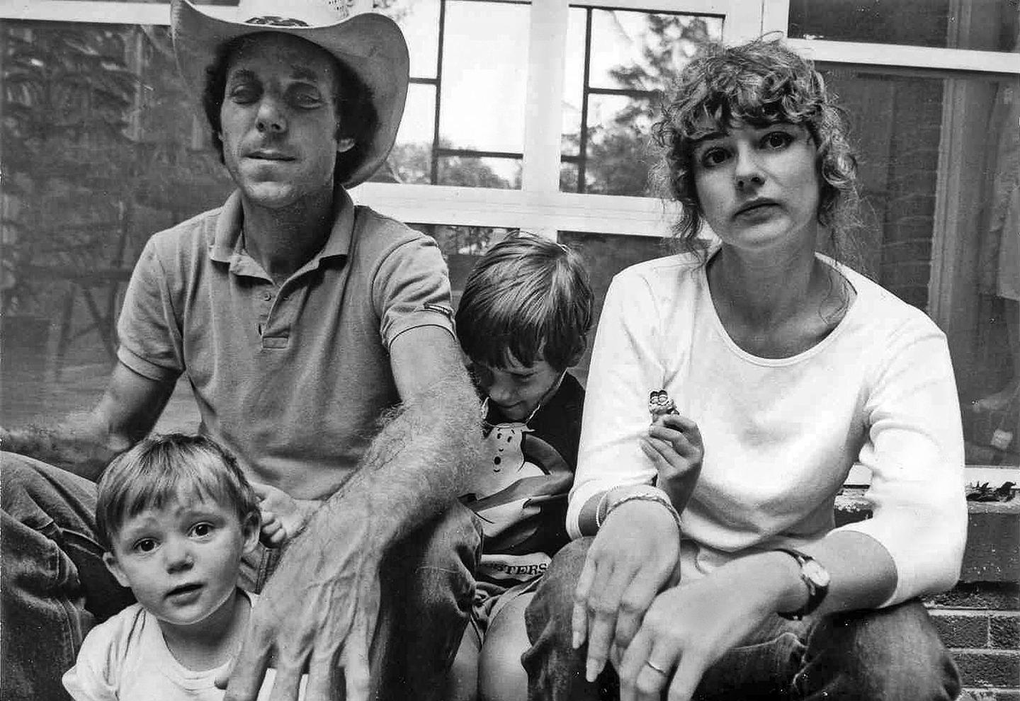 A man in a cowboy hat, a woman, and two children sit together in front of a window.