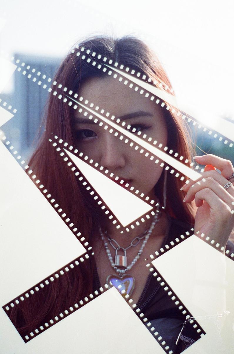A woman with long hair and a necklace is visible through a pattern of film strips.