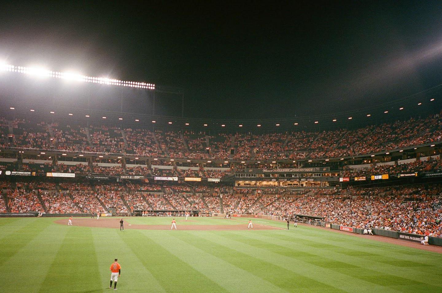 A baseball game is being played at night in a stadium filled with spectators.