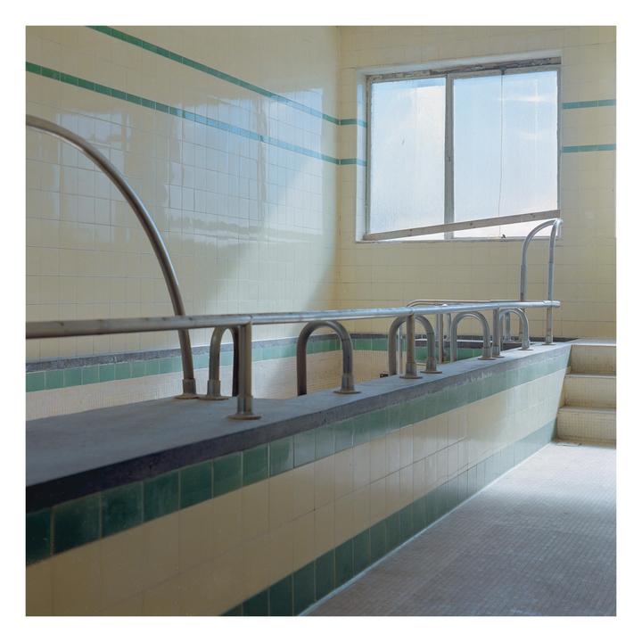 A tiled room with a window and metal railings along a raised edge is visible.