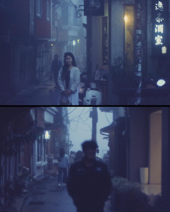 A woman stands on a foggy street in Jiufen, Taiwan, with buildings and a scooter visible.