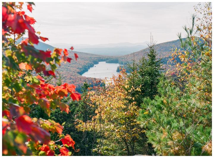 A lake is visible between mountains covered in autumn foliage.