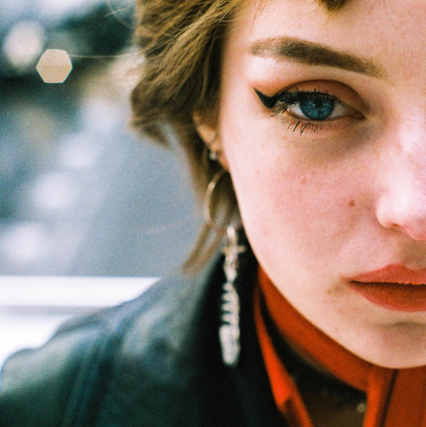 A woman with blue eyes and red lipstick looks directly at the viewer.