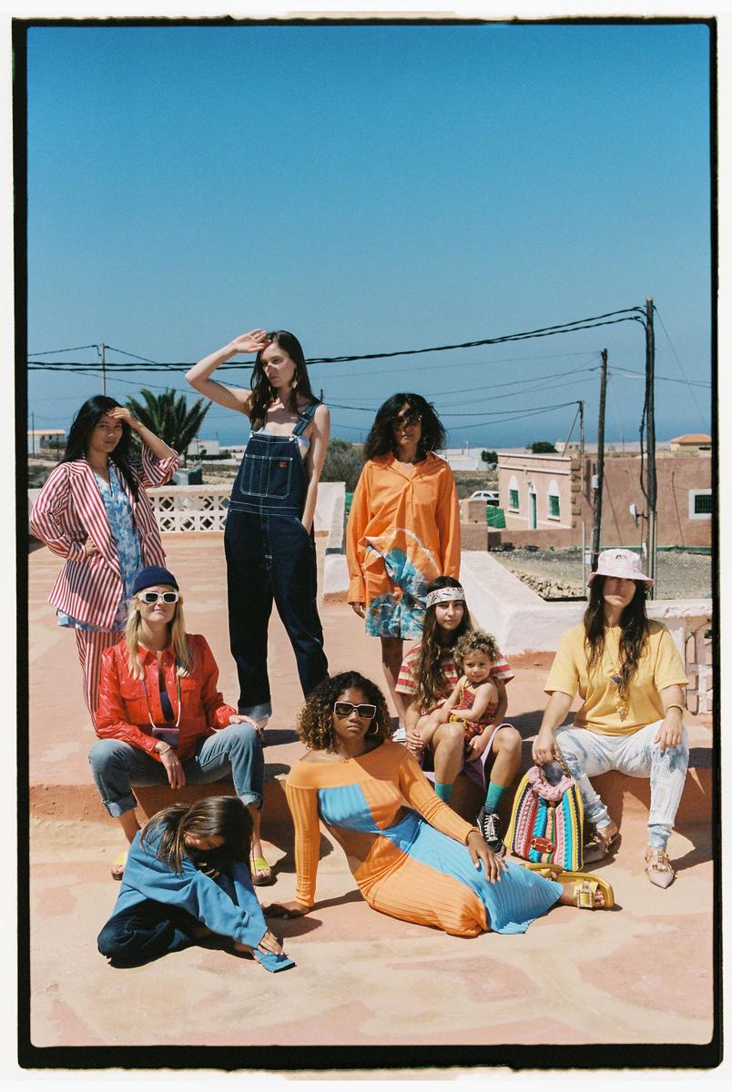 A group of women and children are posing on a rooftop under a clear blue sky.