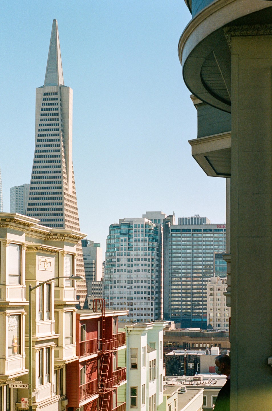 A man looks out over a cityscape with the Transamerica Pyramid visible in the background.