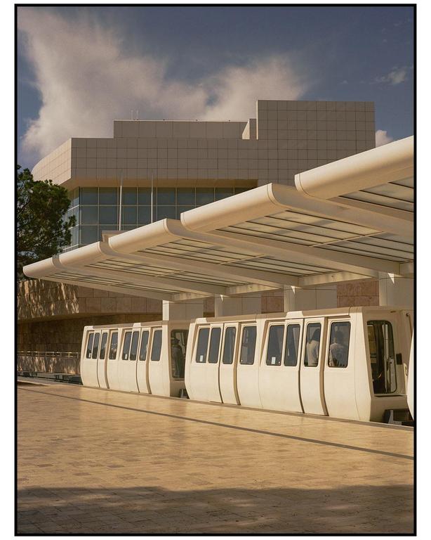 A monorail train is parked at a station with a modern building in the background.