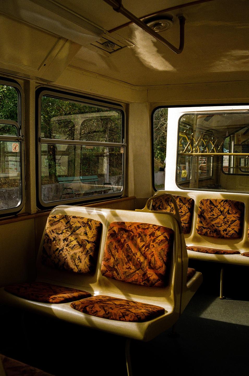 The interior of a bus or tram is visible, with sunlight illuminating the seats and casting shadows.