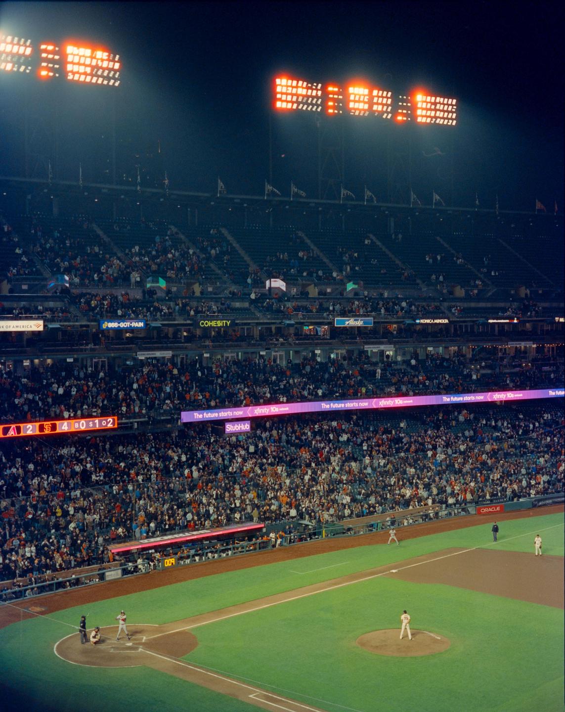 A baseball game is played at night in a stadium full of spectators.