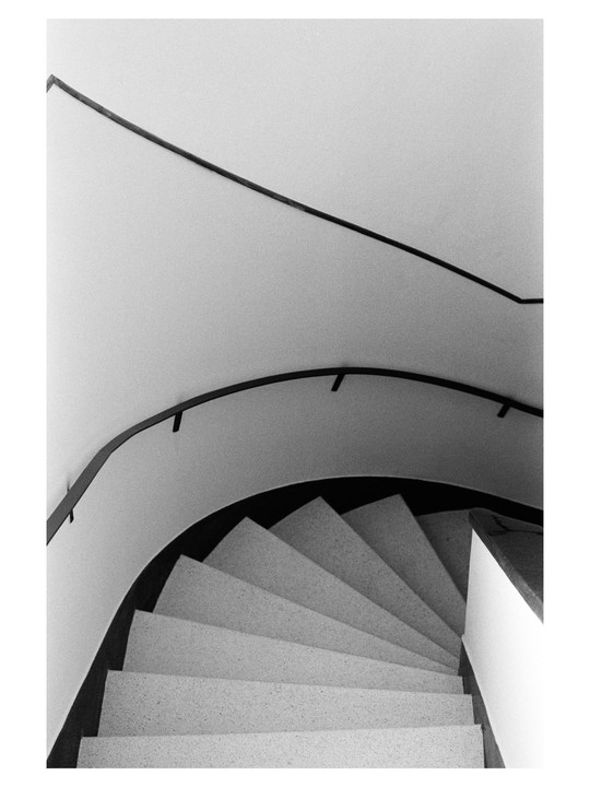 A spiral staircase with a dark handrail curves downwards.