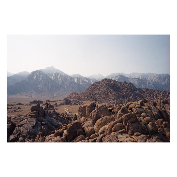 A vast landscape of rocky hills and mountains stretches under a hazy sky.