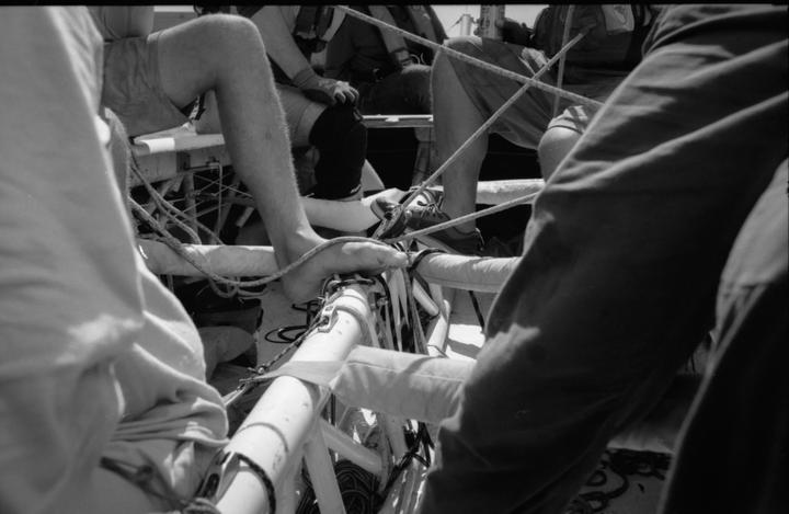A group of people are sitting on a boat with ropes and equipment around them.