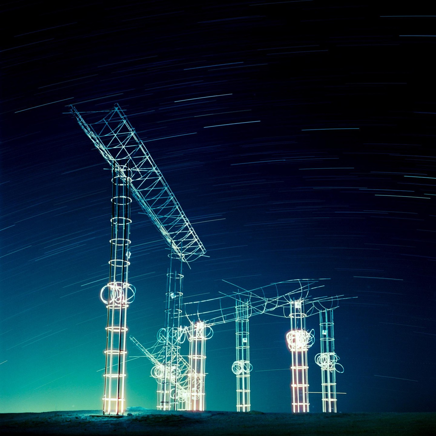 A long exposure shot of illuminated structures under a night sky with star trails.