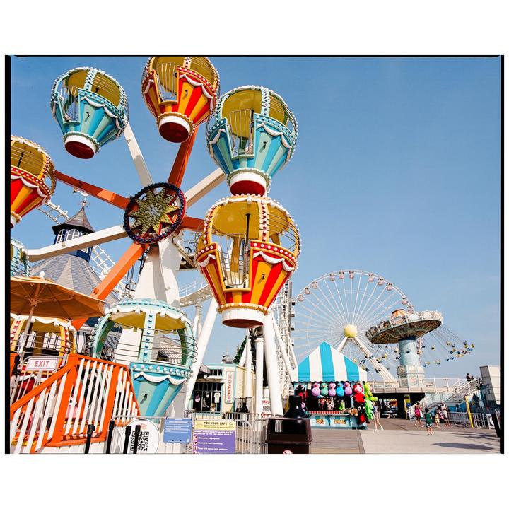 A colorful amusement park ride with hot air balloon-shaped gondolas is visible under a clear blue sky.