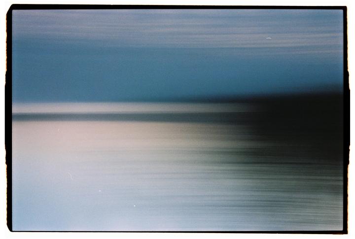 A blurred image shows a blue sky above a light-colored horizon line and a dark, streaky foreground.