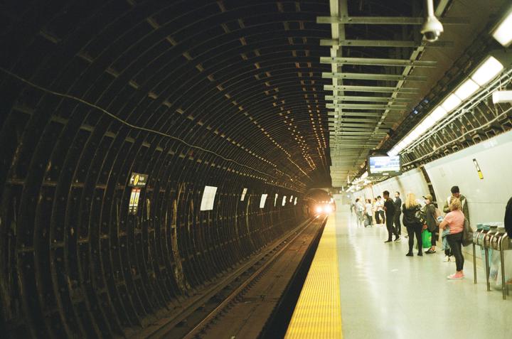 A subway train approaches a station platform where people are waiting.