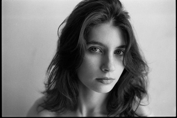 A woman with long, dark hair looks directly at the viewer.